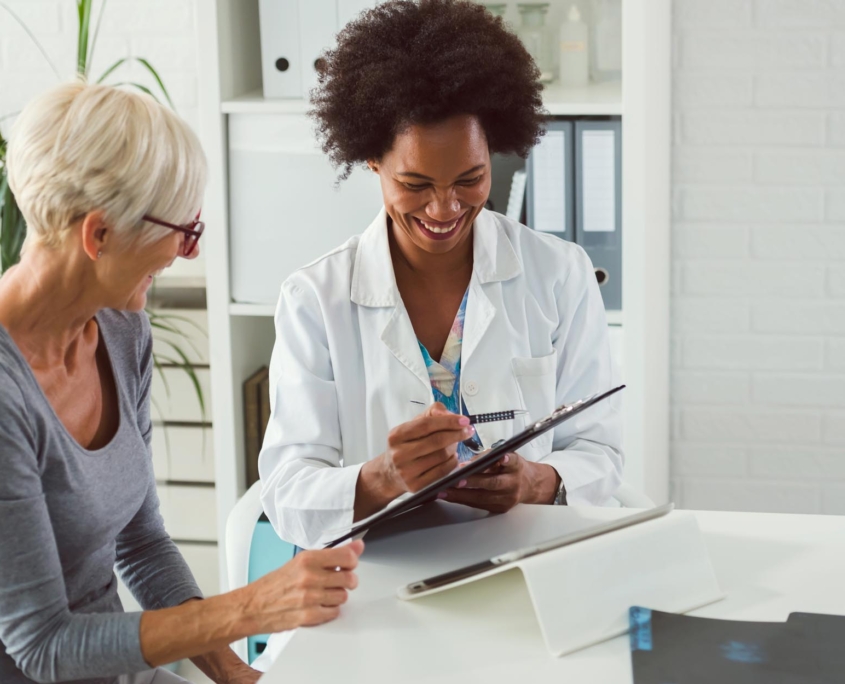 female doctor sits at her desk and chats to an elderly female patient