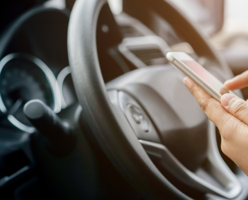 Side view of a woman on her phone while sitting at the steering wheel