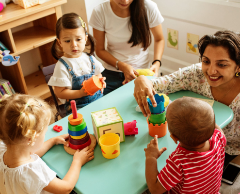 Nursery children playing with teacher in the classroom