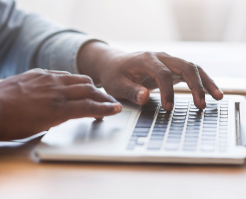 Side view of a man typing on laptop keyboard