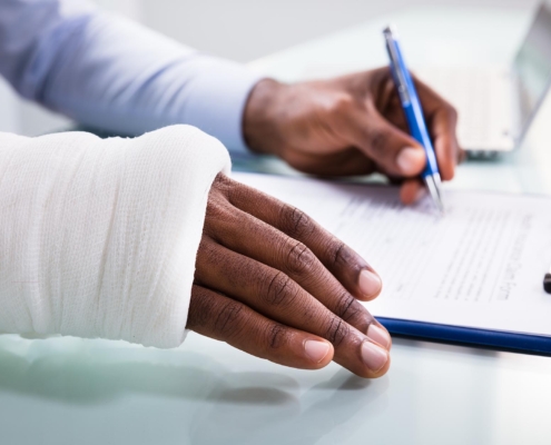 person in cast signing Workers’ Compensation paperwork