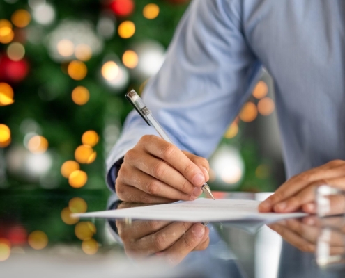 person filling out paperwork infront of christmas tree