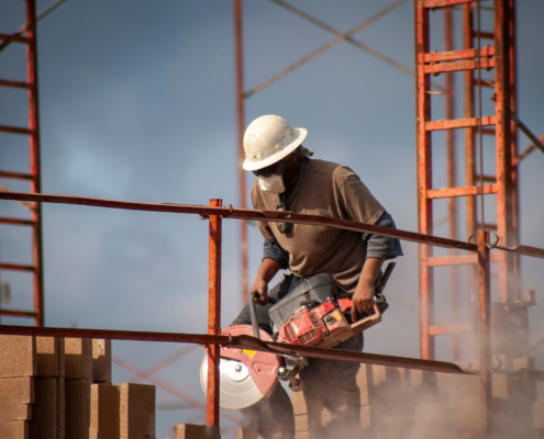 Construction worker wearing a hard hat operating a circular saw